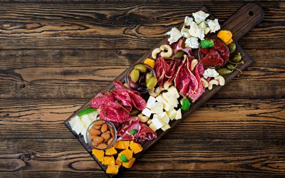 Antipasto catering platter with bacon, jerky, sausage, blue cheese and grapes on a wooden background. Top view